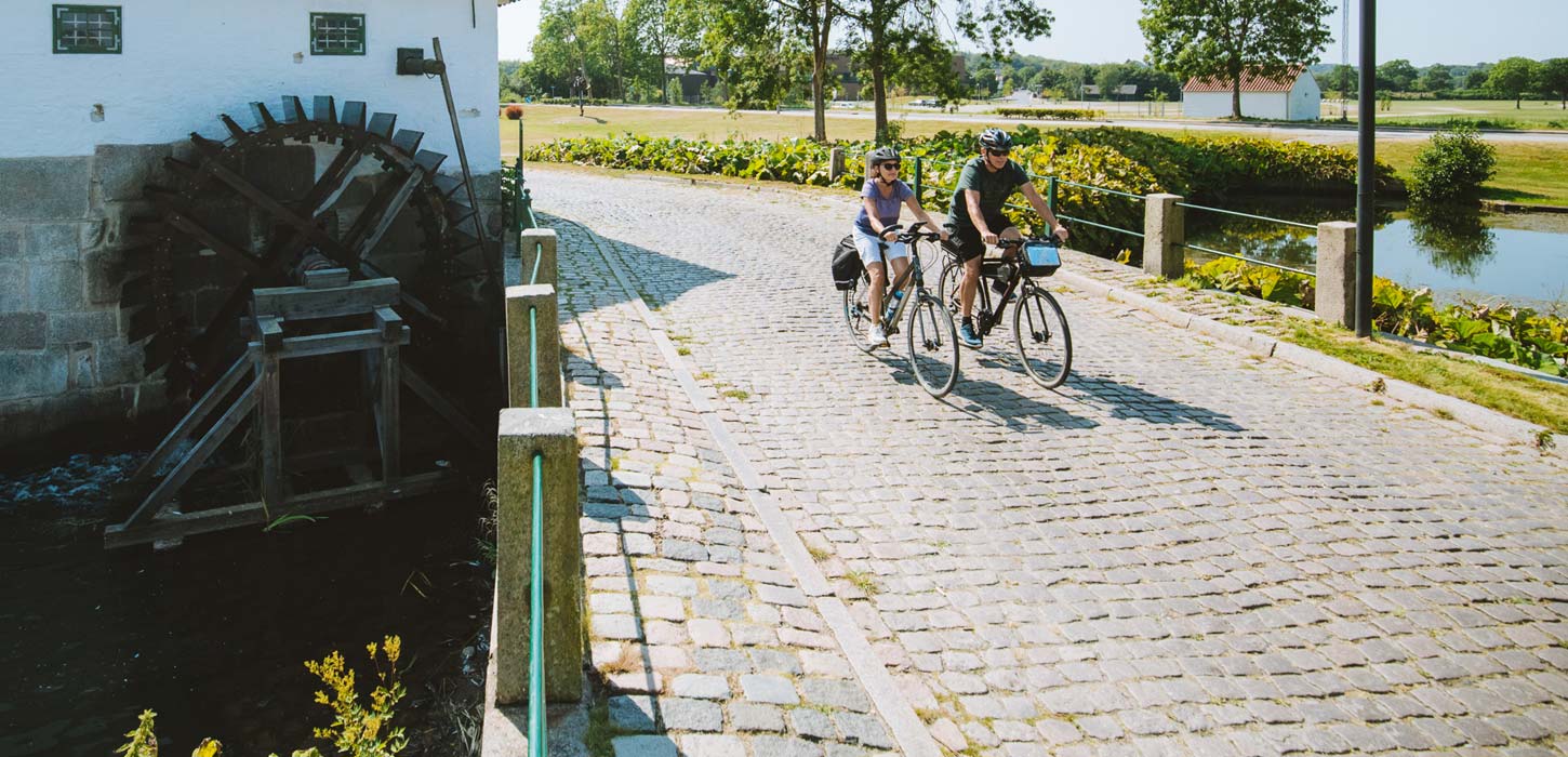 Pärchen fährt Fahrrad an der alten Schlossmühle in Aabenraa