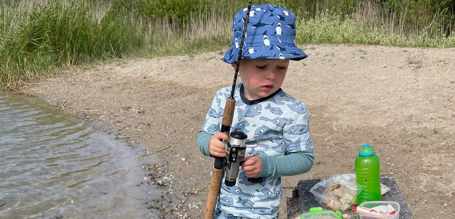 Lystfiskeri ved sø med lille dreng