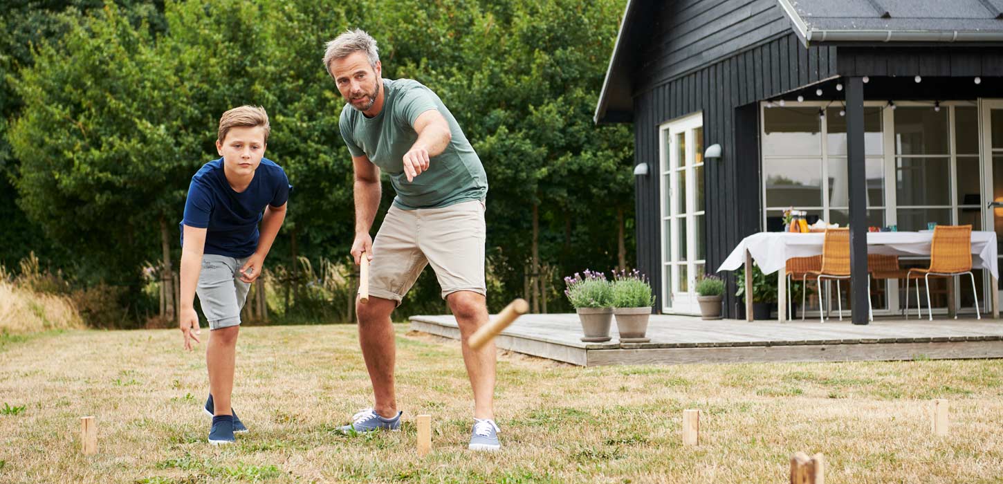 Far og søn spiller Kongespil foran sommerhus