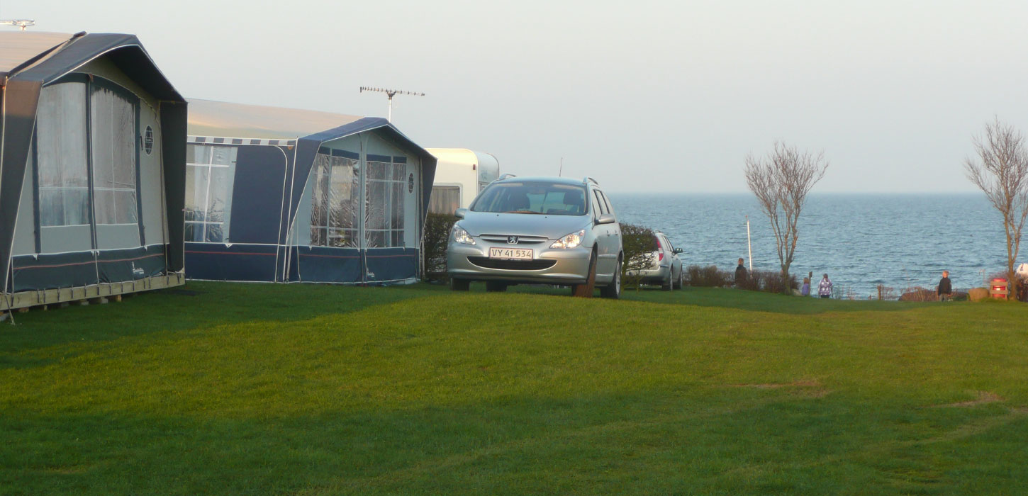 Fortelte og bil med vandet i baggrunden på Gaasevig Camping