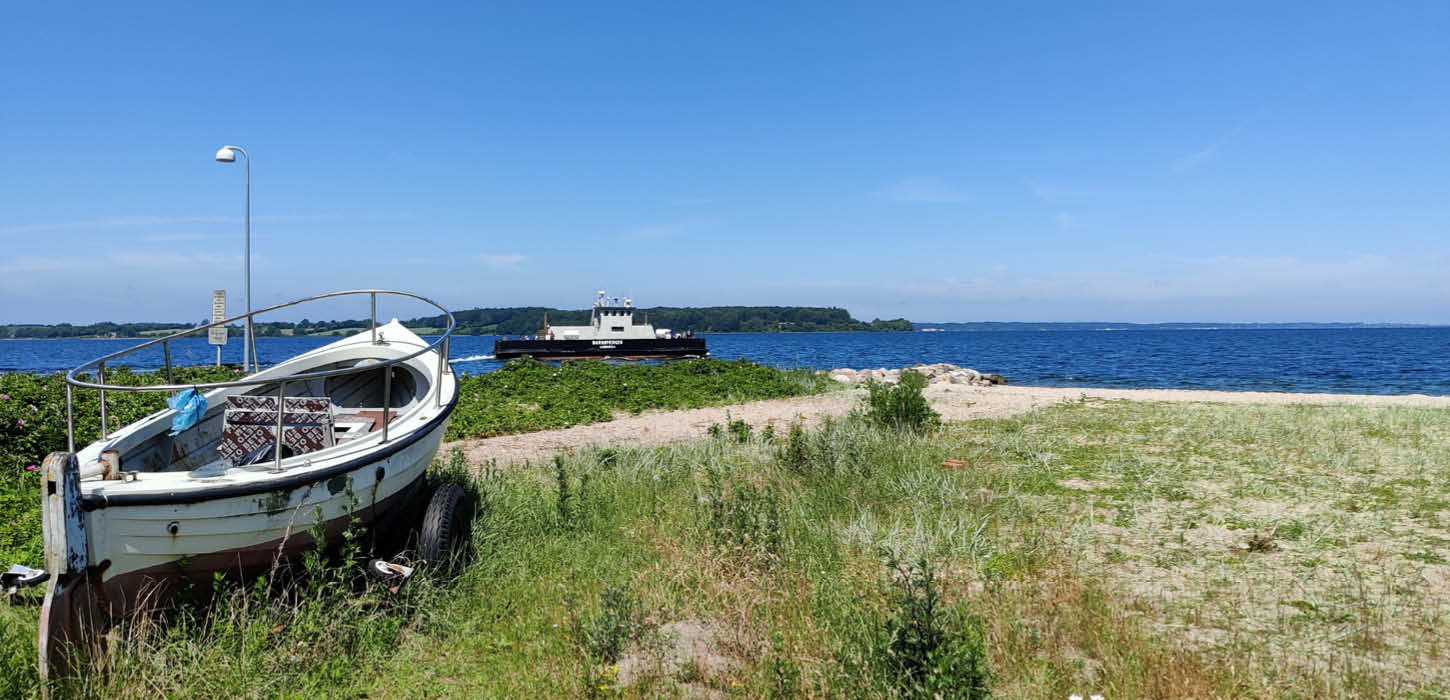 Barsø - Boot am Strand und Fähre im Hintergrund