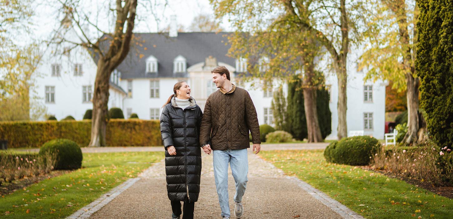 Par vandrer i slotshaven ved Schackenborg Slot i efteråret