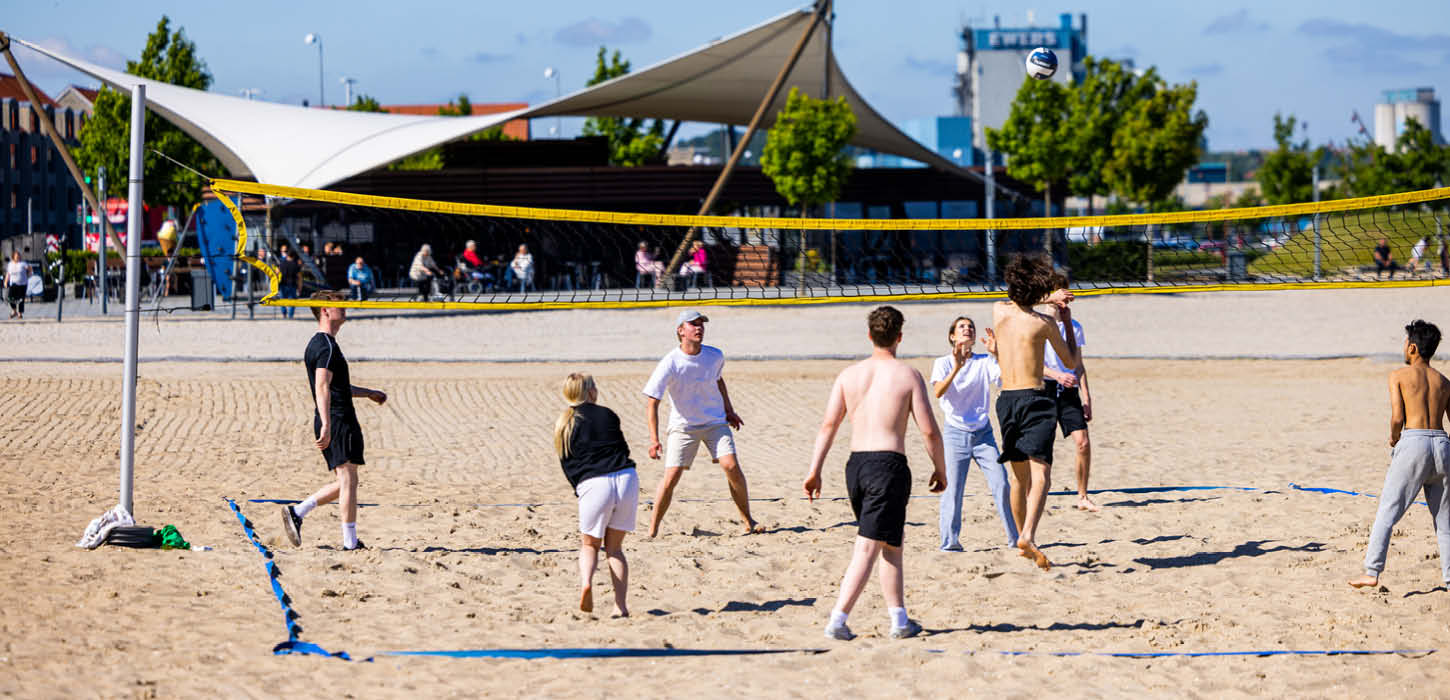 Junge Menschen spielen Volleyball mit einander am Strand von Aabenraa