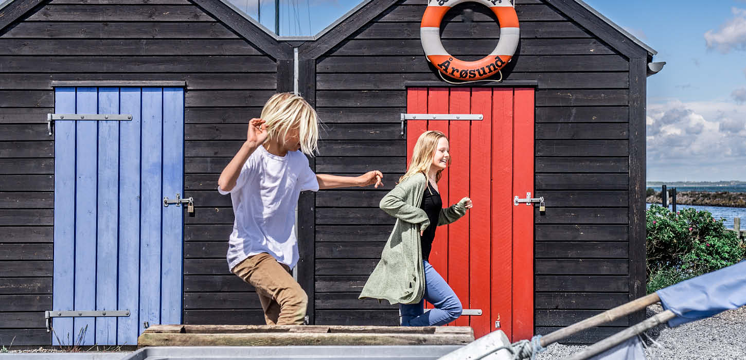 Børn leger ved de små huse på Aarøsund Havn