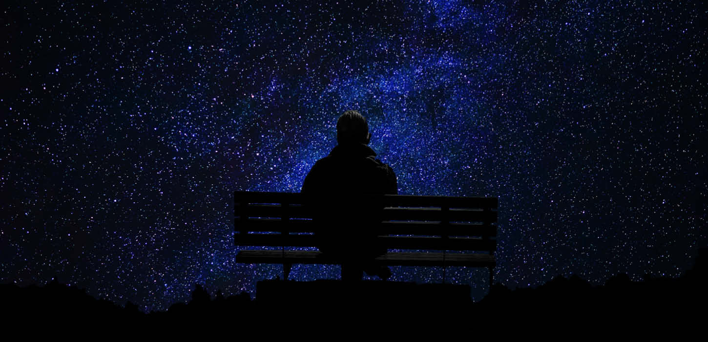 Mørkevandring - person på bænk kigger på en himmel fyldt med stjerner