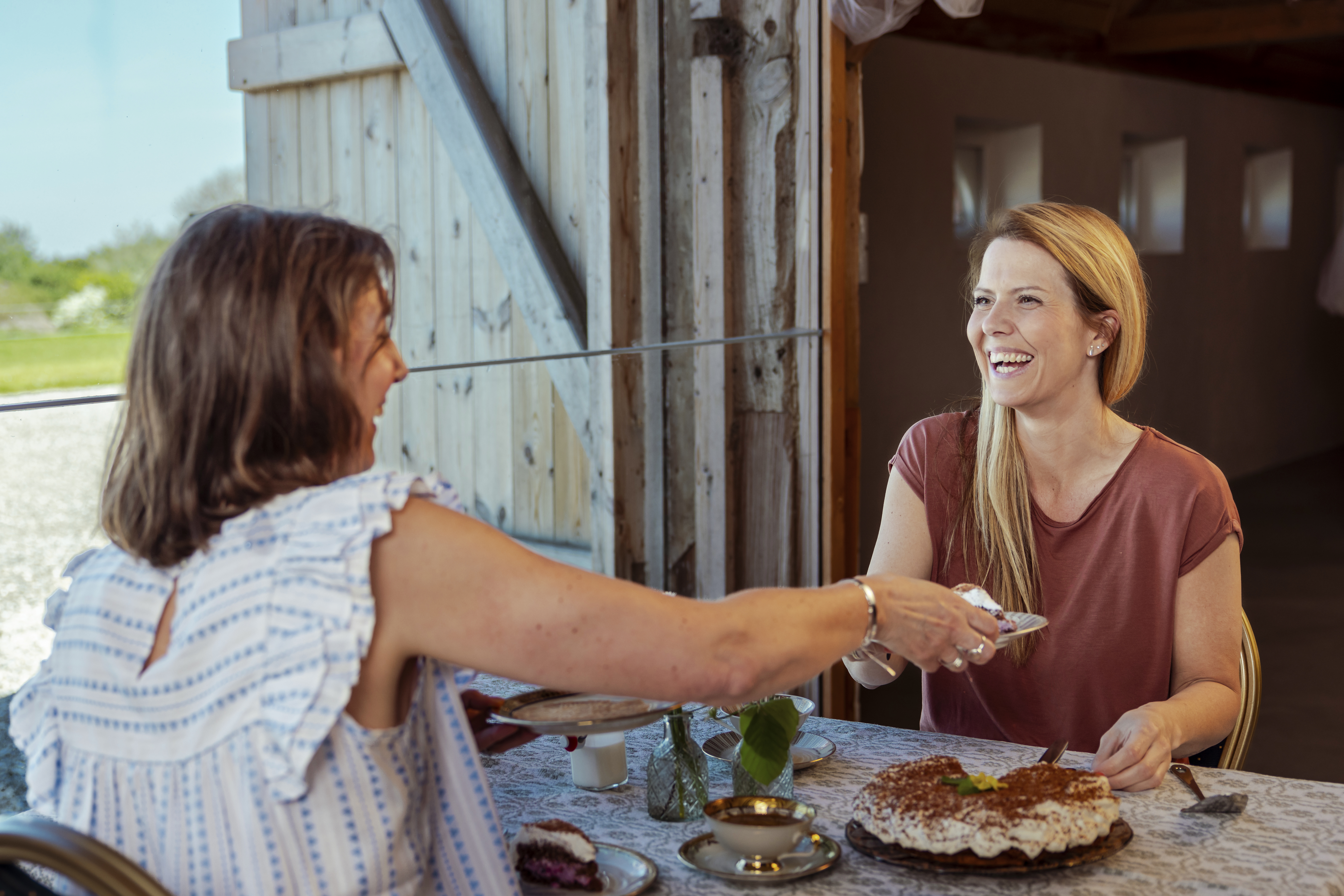 To kvinder hygger og griner til Sønderjysk kaffebord på Klægager